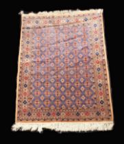 A Signed Pakistani Rug woven in silky threads of predominantly red and blue with repeated geometric