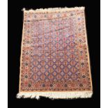 A Signed Pakistani Rug woven in silky threads of predominantly red and blue with repeated geometric