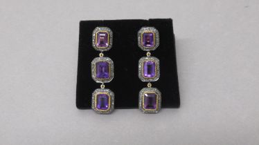 A striking pair of silver-gilt drop earrings each set with 3 emerald-cut amethysts, each