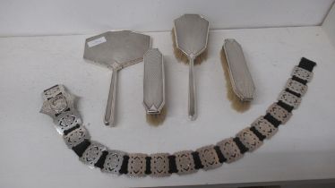 A silver mirror and three brushes and a silver belt