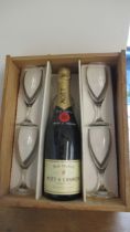 A bottle of Moet & Chandon and four glasses in a wooden case