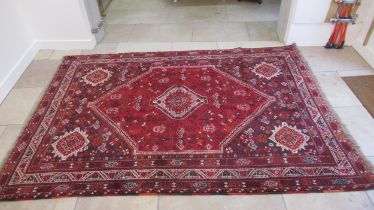 A large red ground hand knotted Persian rug - 294cm x 210cm