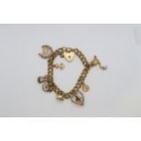 A 9ct yellow gold (hallmarked) charm bracelet - 8 charms with heart lock - approx weight 24.4 grams