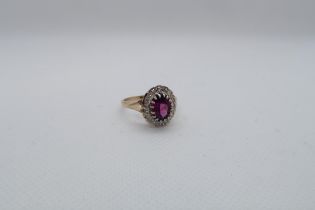 A 9ct yellow and white gold dress ring set with a purplish red rhodolite garnet and a diamond