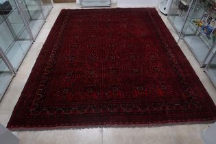 A hand knotted Afgan rug - 4m x 3m - with a deep red field - in good condition and colours