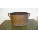 A hand hammered copper log bucket, riveted with twin handles, of oval shape with good patina -