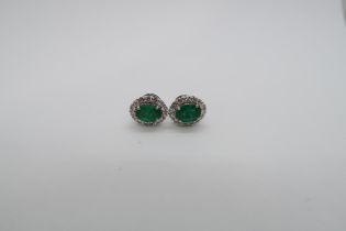 A pair of 18ct white gold oval emerald and round brilliant cut diamond cluster studs - emeralds 1.