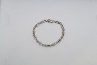 A baguette and round brilliant cut diamond line bracelet in 14ct (hallmarked) white gold - total