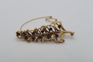 An 18ct yellow gold hallmarked leaf shaped brooch with blue sapphires, approx 6cm, approx 14.3 grams