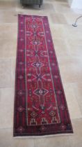 A hand knotted woollen Baluchi rug - 3.05m x 1.02m