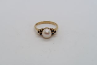 An 18ct hallmarked yellow gold ring with central pearl triple setting sapphire shoulders, size L,
