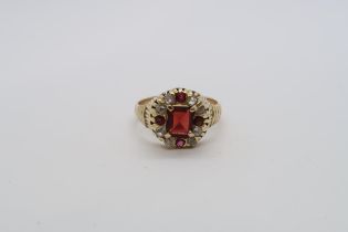 An 18ct yellow gold hallmarked garnet and diamond ring, central emerald cut red garnet set with rose