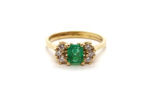 An 18ct yellow gold (tested) emerald and diamond ring, emerald has natural inclusions, diamonds