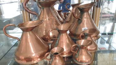 A set of seven graduating copper jugs