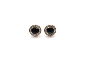 A pair of sapphire and diamond cluster ear studs - each stud with an oval cut sapphire, each