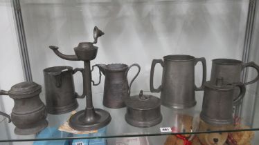 Eight items of antique Pewter including an oil lamp, jugs and a twin handle mug inscribed HMS