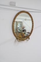 A gilt framed oval mirror with triple candle holder - 80cm x 60cm