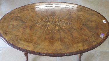 A 19th century walnut and marquetry oval centre table on turned and carved legs and a cross