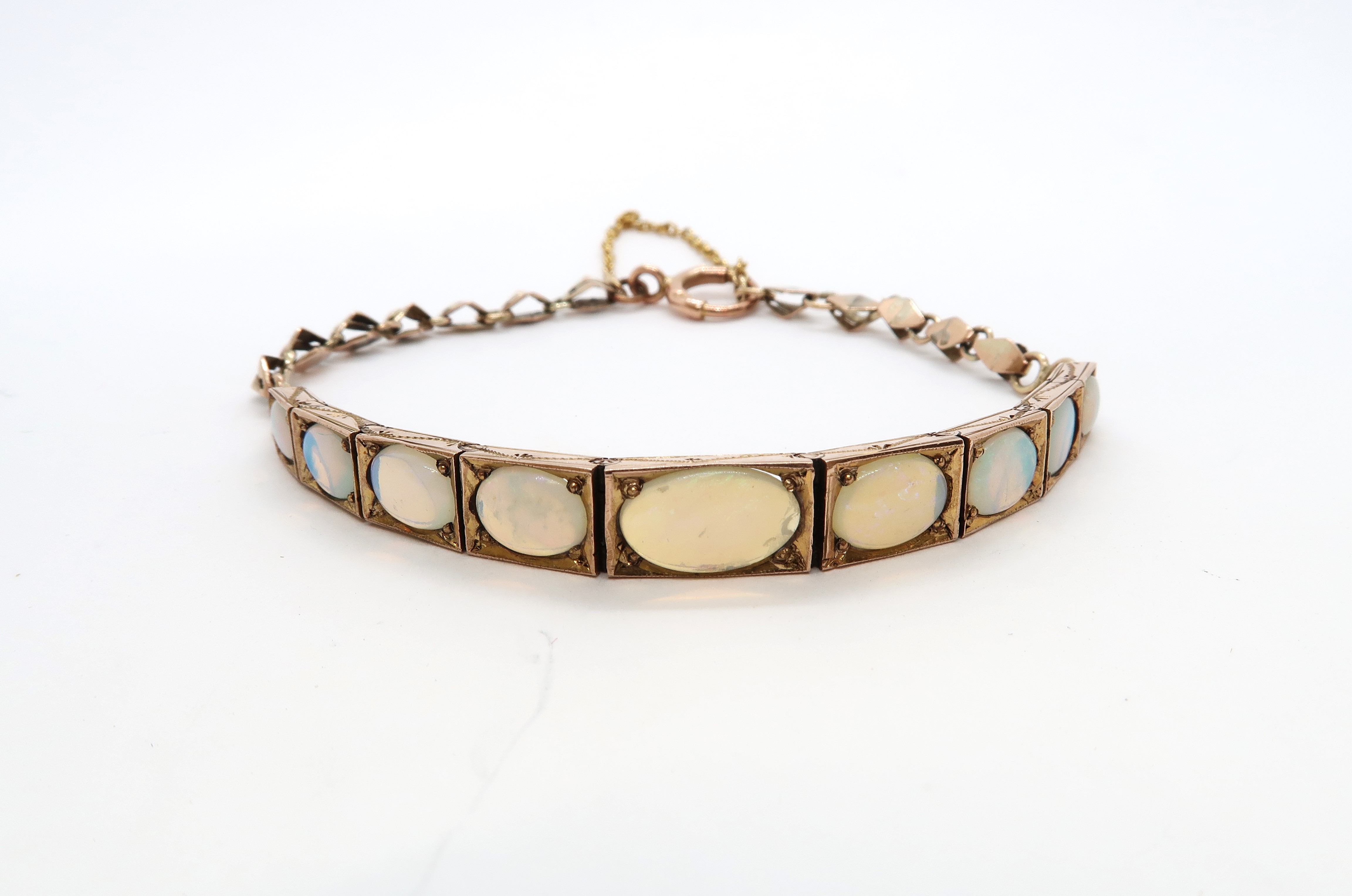 A 9ct yellow gold and opal articulated bracelet with nine graduated opals - 7.1 grams