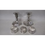 A pair of silver candle sticks and three silver serviette rings, approx 11 troy oz