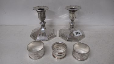 A pair of silver candle sticks and three silver serviette rings, approx 11 troy oz