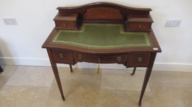 An Edwardian mahogany and inlaid bow fronted ladies writing desk with a leather inset top over three