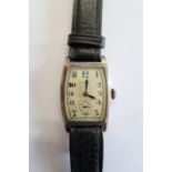A vintage silver cased wristwatch on a leather strap, working in saleroom