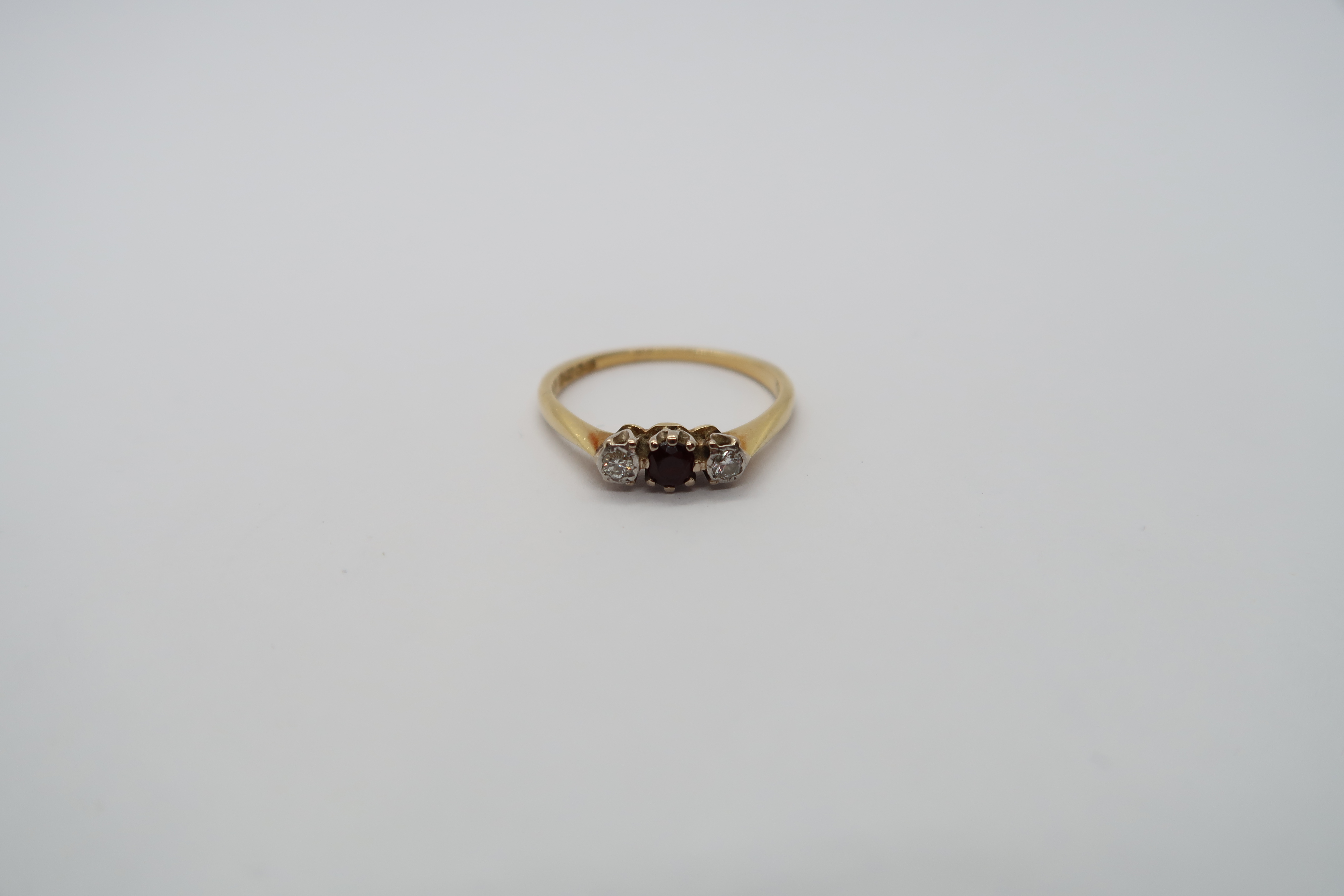 An 18ct hallmarked yellow gold three stone ring with diamonds and garnet, size L, approx 2 grams