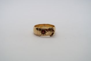 An 18ct hallmarked yellow gold buckle ring with red garnet, size R, approx 8.5g