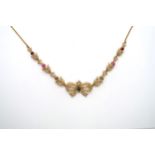 A seed pearl and gem set necklace, with central bow and foliate lines to the curb link chain. Gems