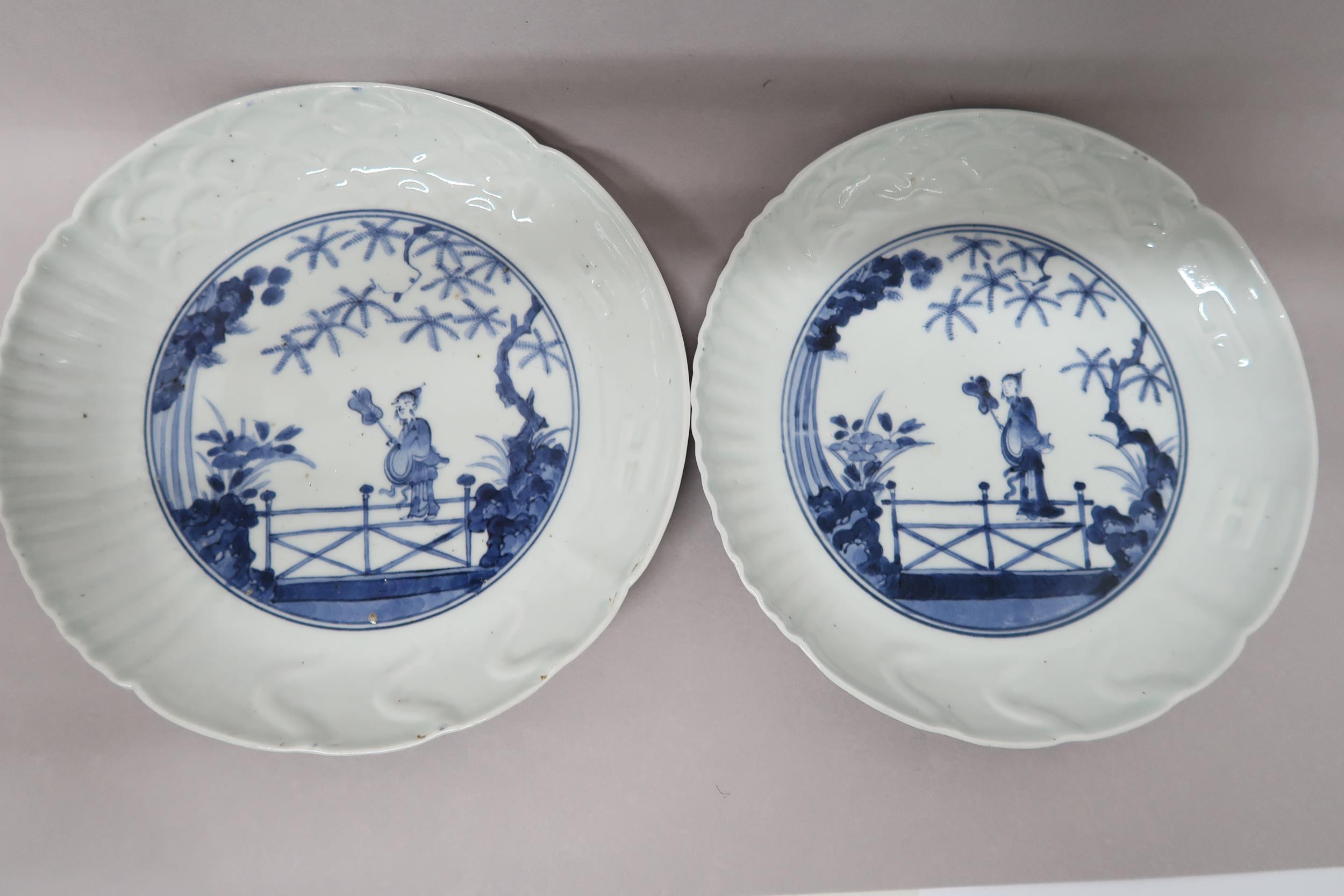 Two Oriental blue and white plates decorated with figure on bridge with foliage to background, 21.