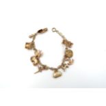 A 9ct gold panel link bracelet suspending ten assorted charms. Weight 15.19 grams.