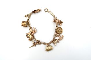 A 9ct gold panel link bracelet suspending ten assorted charms. Weight 15.19 grams.