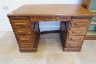 A 1930s oak desk with 9 drawers and panelled sides, 128cm wide x 76cm deep x 78cm high