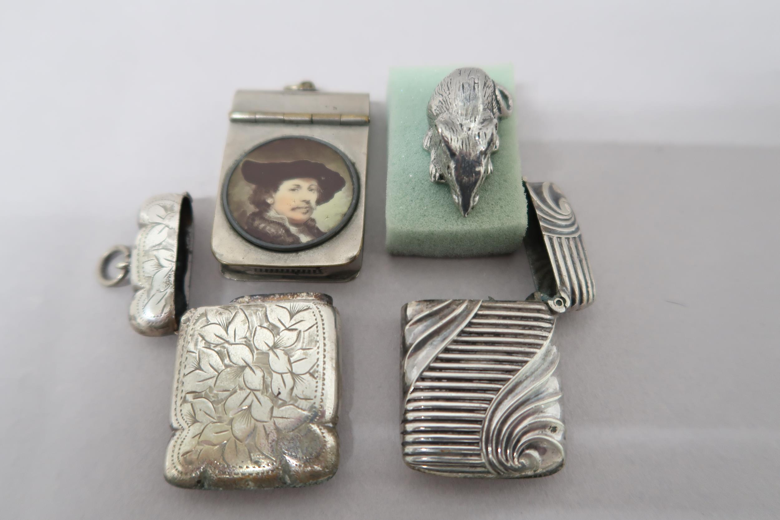 Three white metal vestas, one engraved with foliate field and central reserve, one with ribbed