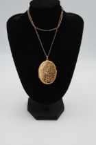 A 9ct gold oval locket with scroll decoration to the front case and a brooch fitting to the