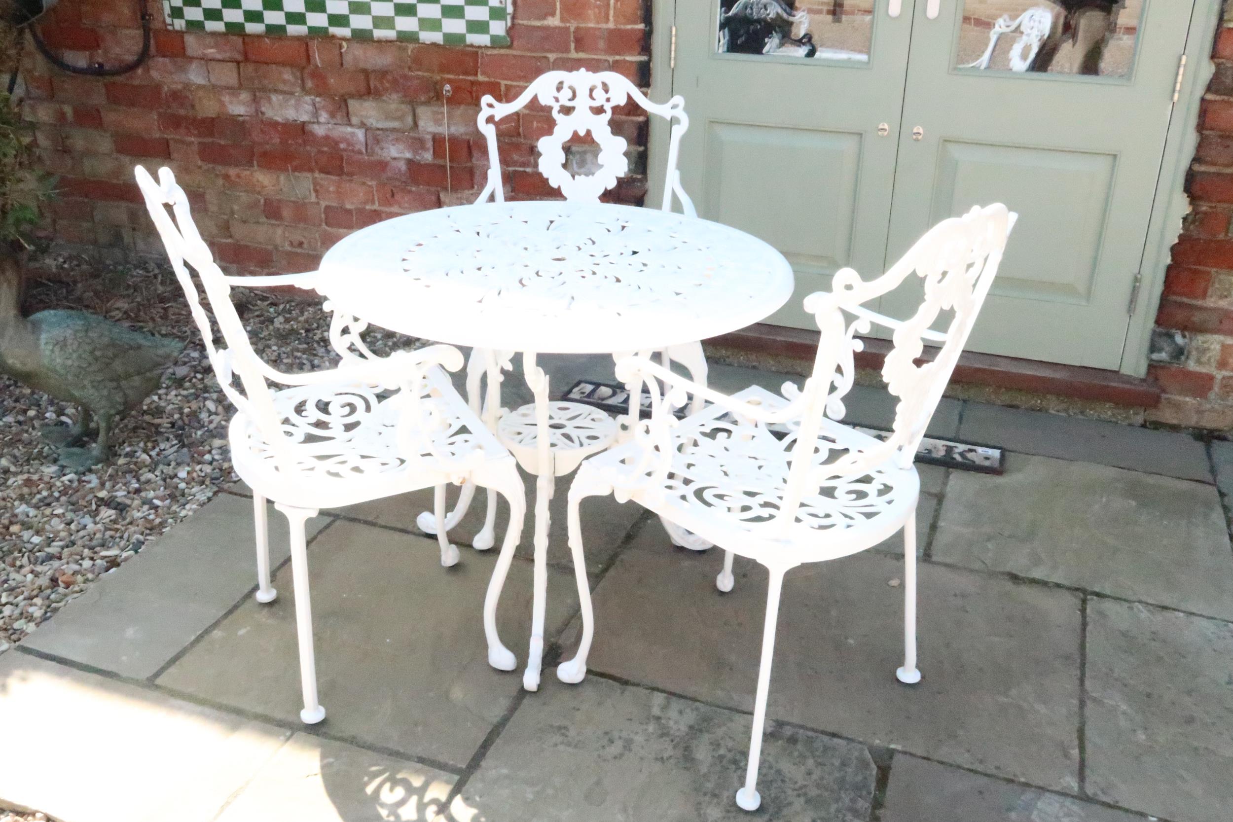 A cast iron garden table and three chairs - Diameter 81.5cm x Height 68cm