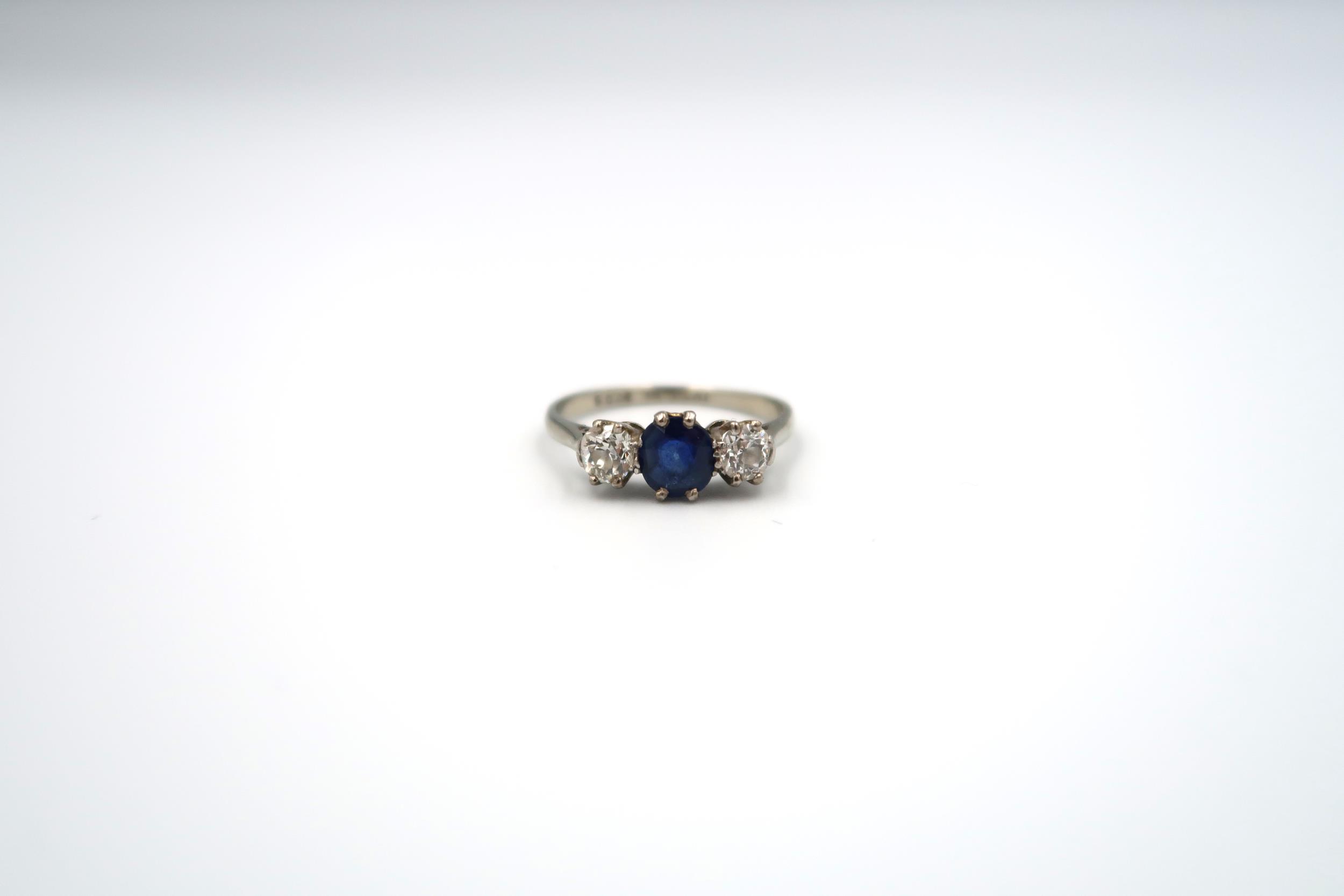 A sapphire and diamond three stone ring. The off round central sapphire to the old cut diamonds.