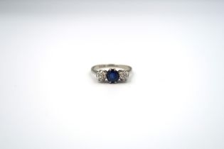 A sapphire and diamond three stone ring. The off round central sapphire to the old cut diamonds.