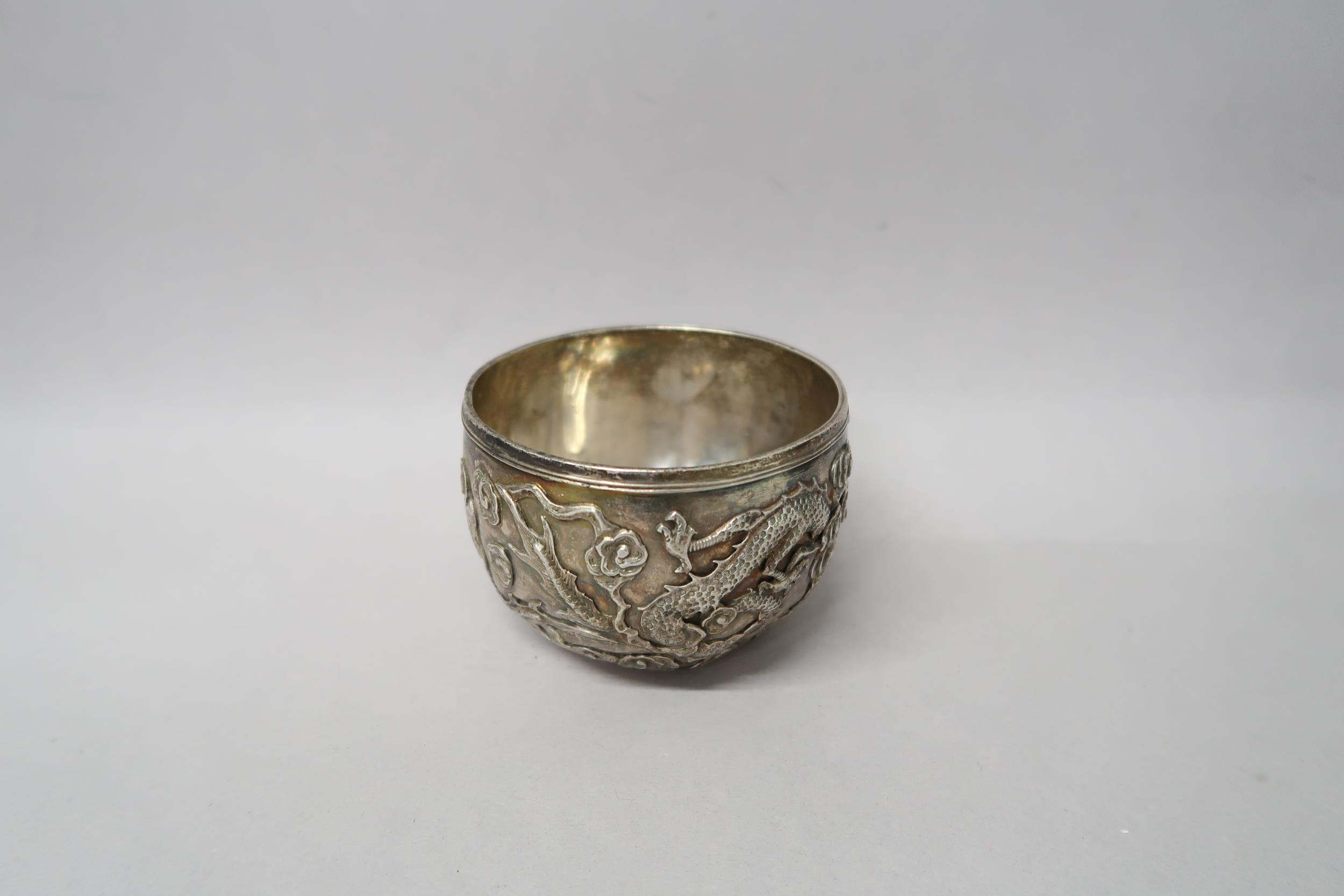 A Chinese silver bowl marked 90 decorated with opposing dragons amongst foliage