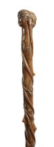 A TREEN WALKING STICK 19TH CENTURY carved with a 'Green Man' style head above a stem carved with