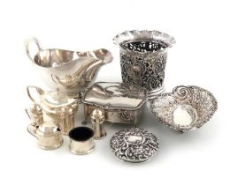 A mixed lot of silver items, comprising: a sauceboat, pierced bottle holder, a dressing table pot (