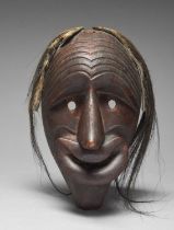 An Iroquois False Face Society mask Eastern Great Lakes carved with a furrowed forehead, pierced