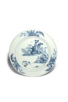 A large delftware charger, c.1760, probably Dublin, painted in blue with a pagoda beside rockwork,