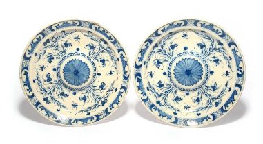 A pair of large Delft chargers, 18th century, the wells raised or embossed and each decorated with a