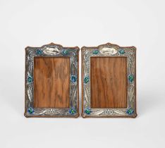A pair of silver and enamel photograph frames, on wooden easel backs, each stamped in low relief