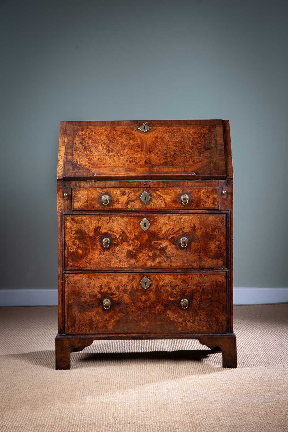 A SMALL GEORGE II BURR WALNUT BUREAU C.1735 with cross and feather banding, the hinged fall with