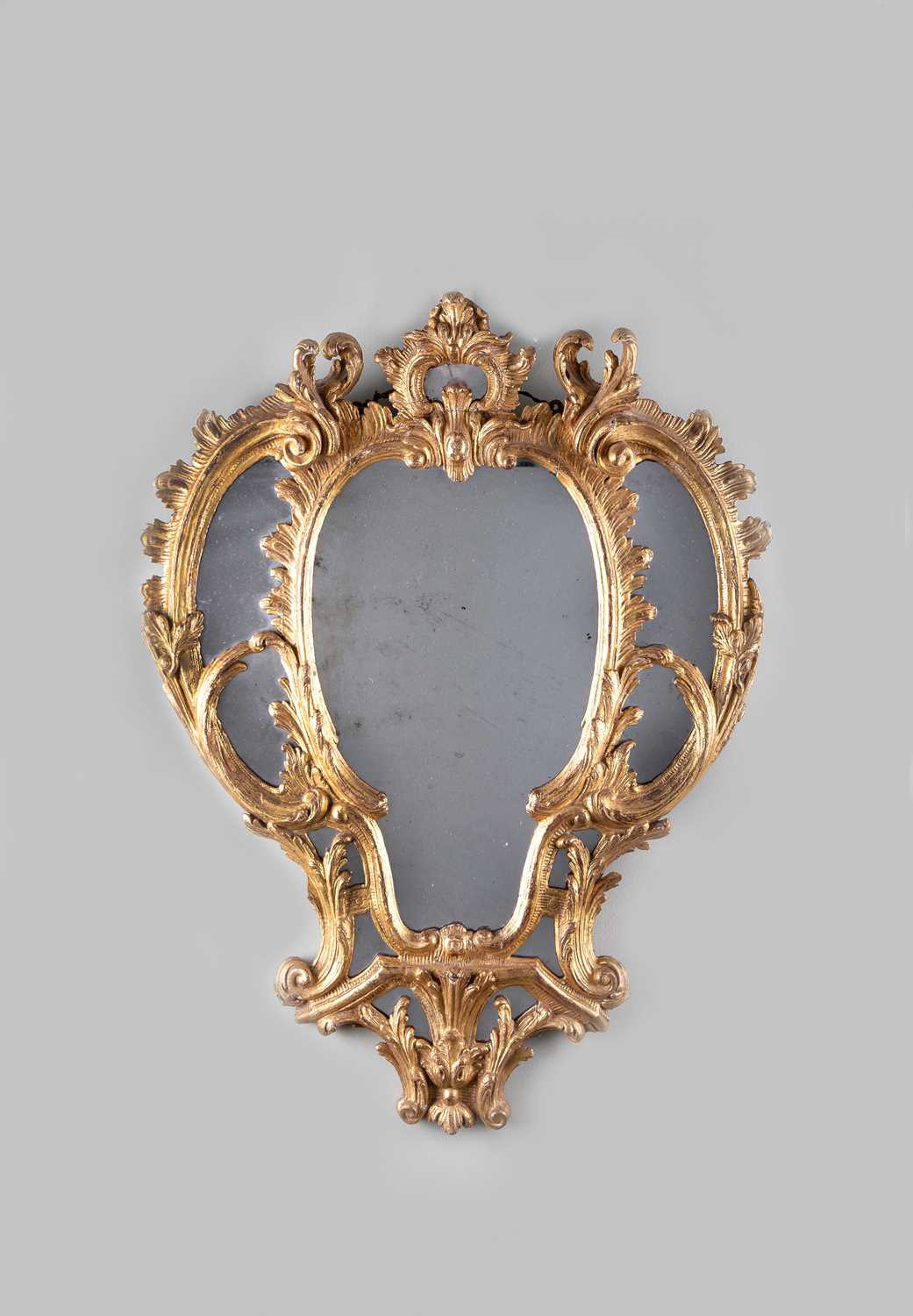 AN EARLY GEORGE III GILTWOOD MIRROR C.1760 with composite plates within a finely carved leaf and