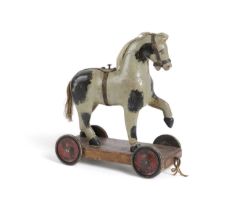 A PAINTED WOOD TOY PULL-ALONG HORSE EARLY 20TH CENTURY grey with black patches, on a four wheeled