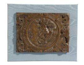 A CARVED OAK PANEL EARLY 17TH CENTURY decorated with a cherub in a circular frame with 'C' scroll